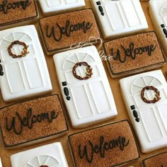 decorated cookies with welcome signs and wreaths are arranged in rows on a wooden surface