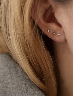 a close up of a person wearing a pair of ear piercings on their ears