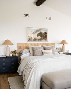 a bedroom with a bed, dresser and two lamps on either side of the bed