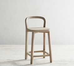 a wooden stool sitting on top of a hard wood floor next to a white wall