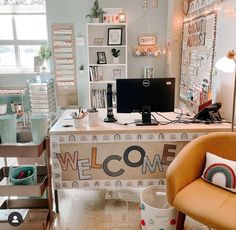 a desk with a welcome sign on it in a room filled with shelves and chairs