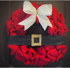 a red wreath with a white bow and black ribbon