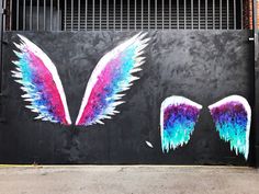 an image of colorful wings painted on the side of a building