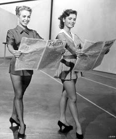 two women in short skirts are holding newspapers