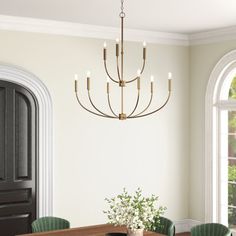 a dining room table with green chairs and a chandelier hanging from the ceiling