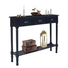 a black console table with two drawers and three candles on the top, along with other decorative items