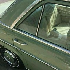 the interior of a green car with its door ajar and seat up, parked in a parking lot