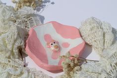 a pink and white bowl sitting on top of a table next to some crochet