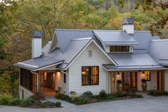 a white house with metal roofing in the woods