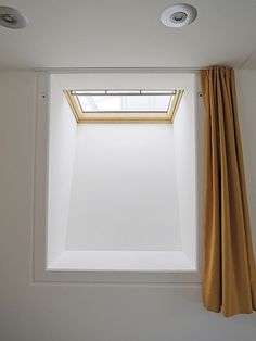 two lights are on in the corner of a room with a skylight above it