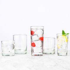 four glasses filled with different types of ice and fruit on top of a marble counter