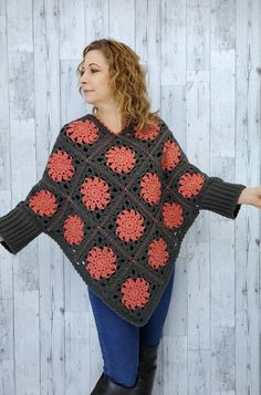 a woman is wearing a crocheted shawl with red and black flowers on it