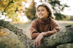 a woman sitting on top of a tree branch