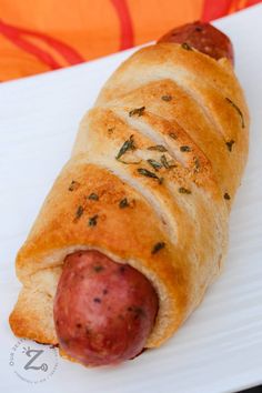 a hot dog wrapped in bread on a white plate