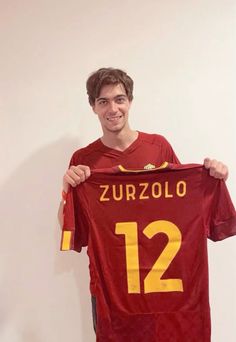 a man holding up a soccer jersey with the number 12 on it