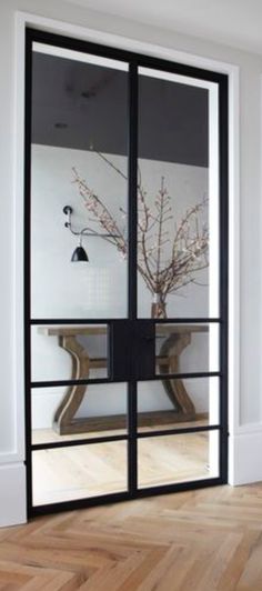 an empty room with wooden floors and black glass doors that lead into the dining area