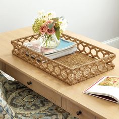 a wooden table topped with a basket filled with books and flowers on top of it