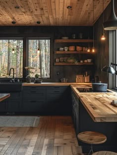 a kitchen with wood flooring and black cabinets in the center, surrounded by windows