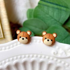 two small brown teddy bears sitting on top of a white plate