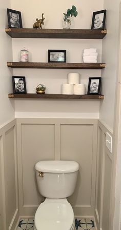 a white toilet sitting in a bathroom next to two shelves filled with pictures and candles