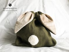 a green bag with a white dot on the side and a brown bunny ears inside