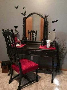 a red chair sitting in front of a desk with a mirror on top of it