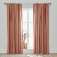 a room with a large window and a rug in front of the window that has pink curtains on it