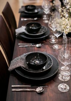 the table is set with black plates and silverware