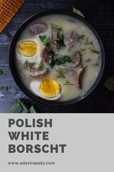 polish white borsch with eggs and herbs in a black bowl on a wooden table