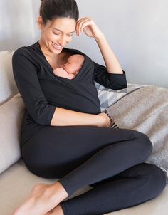 a woman sitting on top of a couch holding a baby in her lap and smiling at the camera