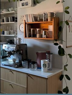 a coffee maker sitting on top of a counter next to a shelf filled with cups