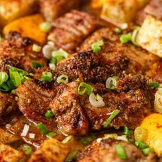 meat and vegetables are being cooked in a pan on the stove with onions, green onions, and potatoes