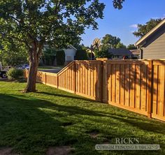 a fenced in yard next to a tree with a truck parked on the other side