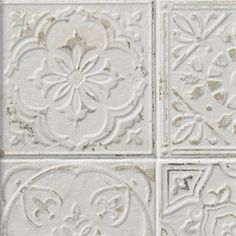 four white tiles with different designs on the sides and one has a flower in the middle