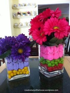 two vases filled with candy and flowers on top of a table