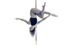 a woman in a black and white bathing suit is on a pole with one leg up