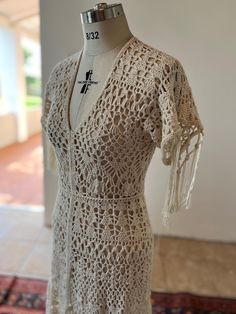 a white crocheted dress on display in a room with tile flooring and walls