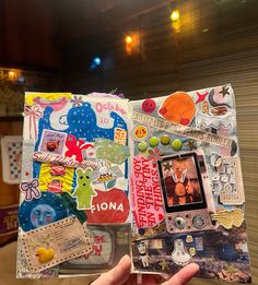 someone holding up a scrapbook with pictures and stickers all over the pages