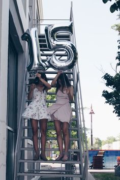 two girls are standing on the stairs with balloons