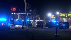 two police cars parked in front of a gas station at night with the lights on