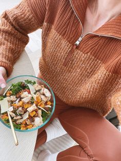 a woman sitting at a table with a bowl of food