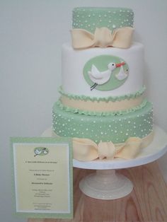 a three tiered cake with a baby duck on the top and a card next to it