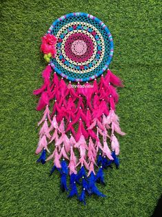 a pink and blue dream catcher is laying on the grass