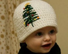 a baby wearing a crocheted christmas tree hat with lights on it's head