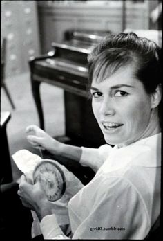 black and white photograph of a woman sitting at a desk with a clock in her hand