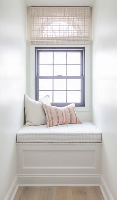 a white window seat with pillows on it