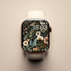 an apple watch with flowers and leaves painted on the front, sitting on a wall