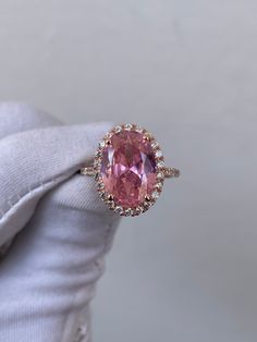 a pink diamond ring sitting on top of someone's finger in front of a gray background