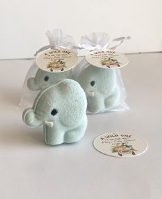 two small stuffed elephants sitting next to each other on a white table with clear bags