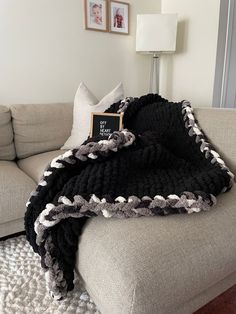 a black and white blanket sitting on top of a gray couch next to a pillow